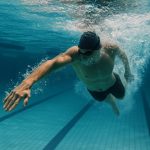 Competitive swimmer performing strokes in a pool, illustrating swimming’s calorie-burning intensity