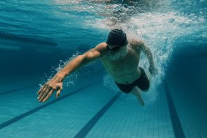 Competitive swimmer performing strokes in a pool, illustrating swimming’s calorie-burning intensity